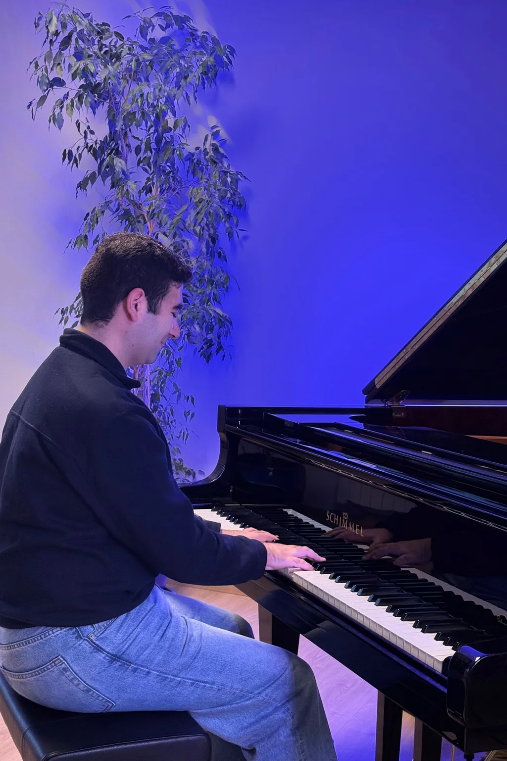 Profesor tocando un piano vertical en un aula luminosa