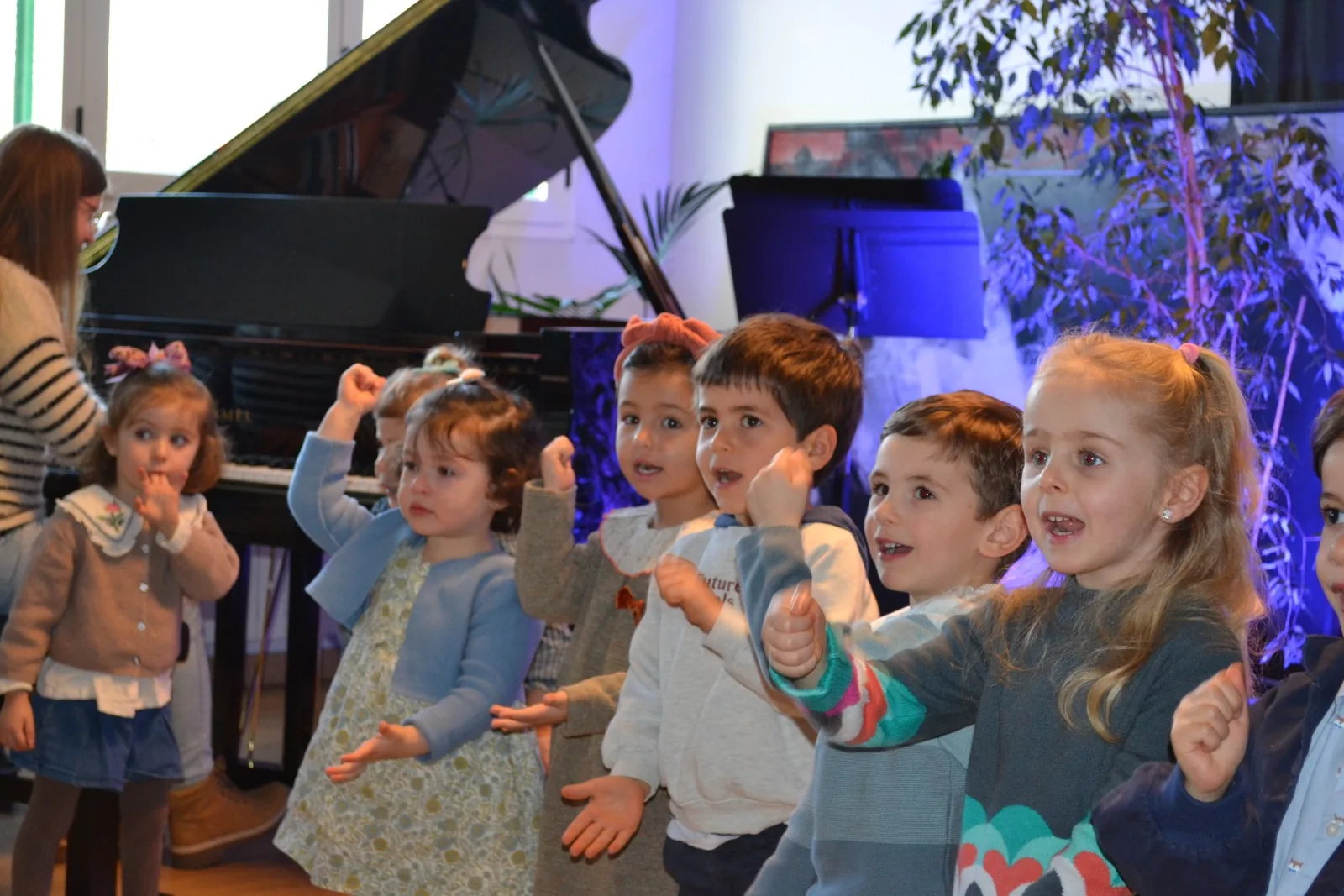 Niños pequeños cantando con gestos delante de un piano en una audición